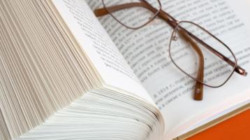 Parte de un libro entre abierto y unos lentes