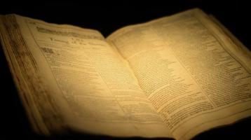 Un libro abierto antiguo iluminado con una luz amarilla