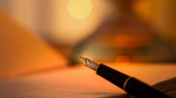 Una pluma y de fondo un libro abierto desenfocado