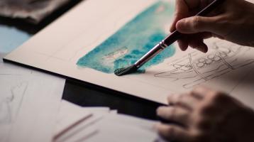 Unas manos sosteniendo un pincel pintando